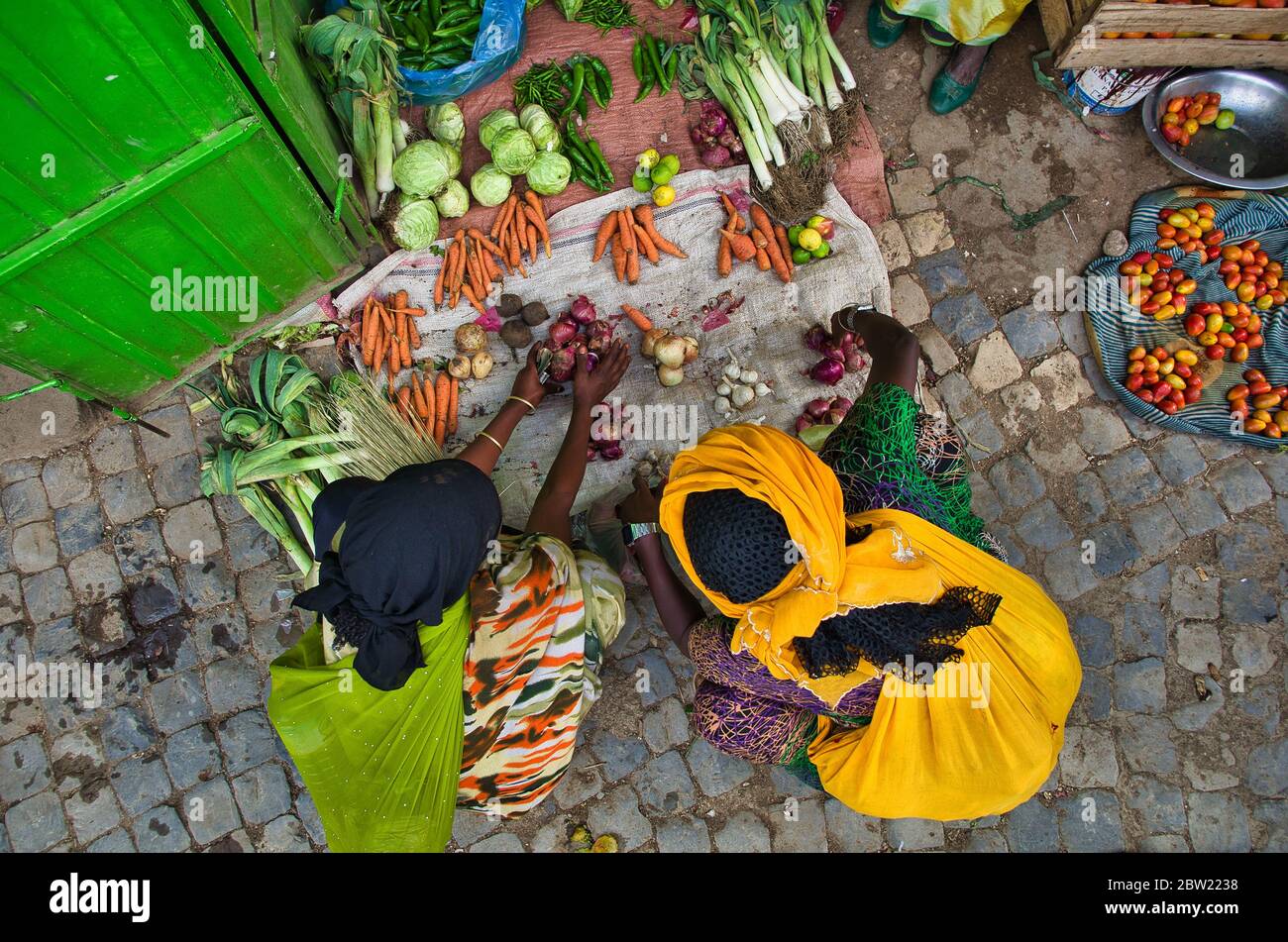 Black women in colorful traditional African costumes crouching at a