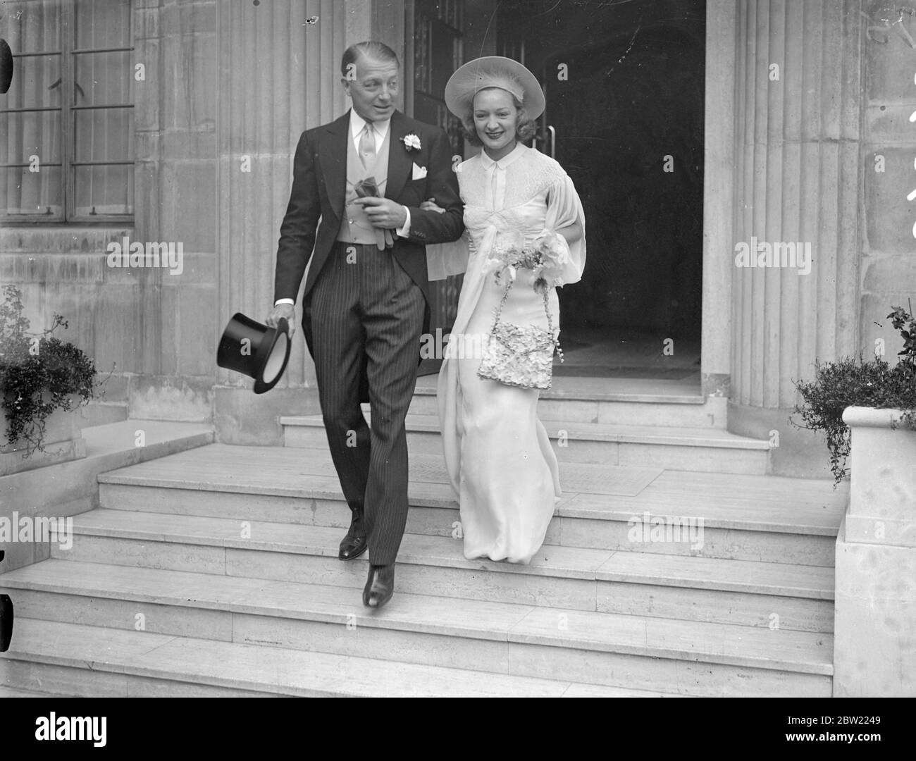 Accompanied by Clive Brooke, the film actor, Miss Florence Desmond, the actress, left her St John's Wood home for the wedding at St James Church, Spanish Place to Mr Charles, Hughesdon, the airmen. The bride set a new fashion by carrying a handbag made of hydrangeas with her initials worked in the flowers, instead of the usual bouquet. 23 September 1937 Stock Photo
