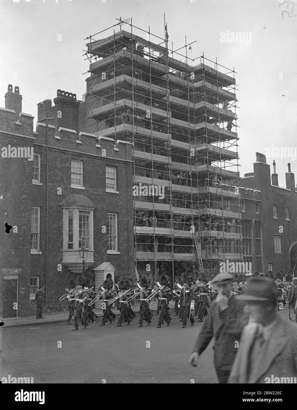 Mass of scaffolding enclosed the gatehouse of St James Palace as the guard was changed. It is encased in scaffolding whilst workmen clean the tower when their task is finish, Londoners will be upwards the the redbrick building almost as it appeared when first constructed. 17 September 1937. Stock Photo