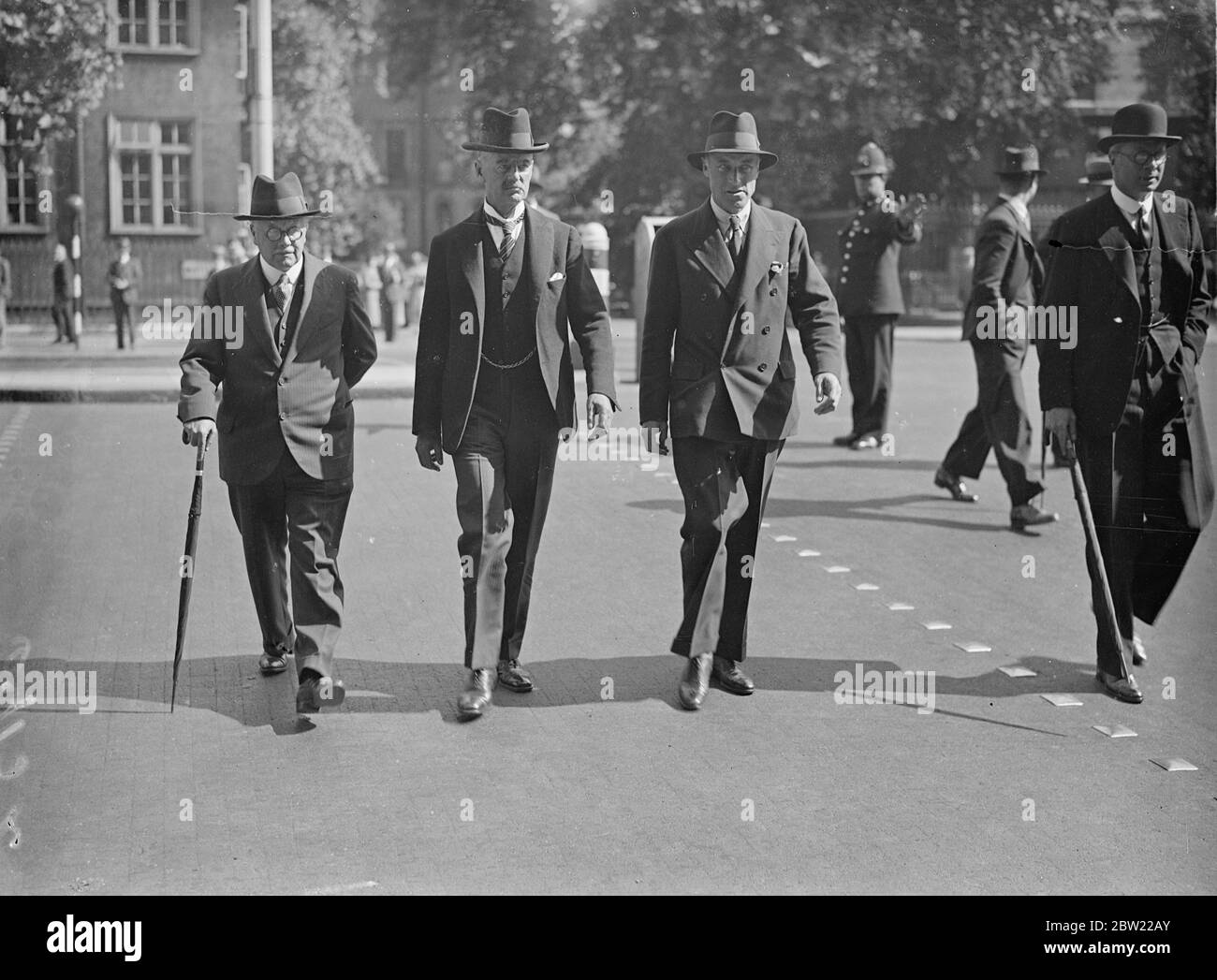 A policeman holding up the traffic the the Premier Mr Neville Chamberlain; Lord Swinton, M Minister and Sir Kingsley worked, health Minister as they crossed Whitehall from the Cabinet office after the morning session of the important cabinet meeting to discuss the anti-piracy plan for the Mediterranean. 8 September 1937 Stock Photo