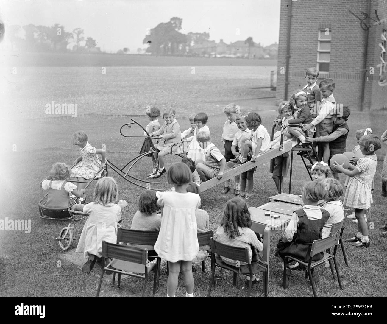 Children at lessons while others play on the fun apparatus. The new Torbett the elementary school has been opened at Ilford. With accommodation 5000 children school has two holes to film projection rooms, wireless equipment with loudspeakers in every room, and a tiny tots department with rocking horses helter-skelter is very cycles a subway is being constructed under the road and five points to give children access into the playground safety the school cost 40,000 build. 13 September 1937. Stock Photo