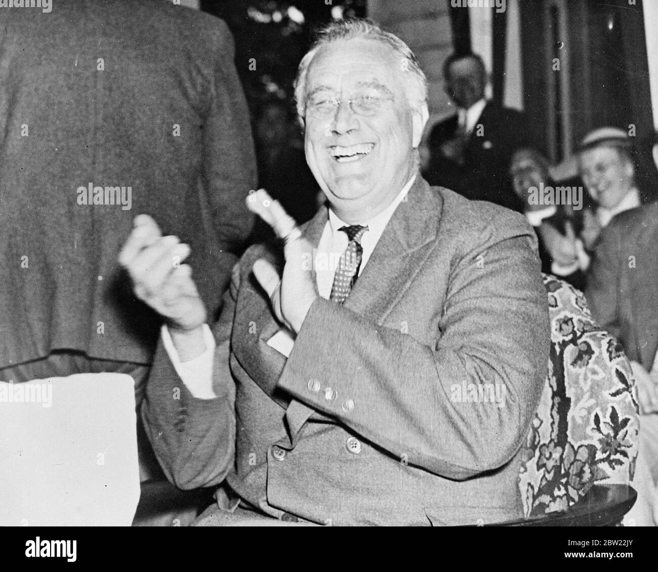 President Franklin Roosevelt, all his Supreme Court and New Deal worries temporarily forgotten, laughs heartily and applauds one of his host's topical observations when visited by Moses Smith, a tenant farmer on his Hyde Park estate, New York, with Bernard Baruch, the financier. 22 September 1937 Stock Photo