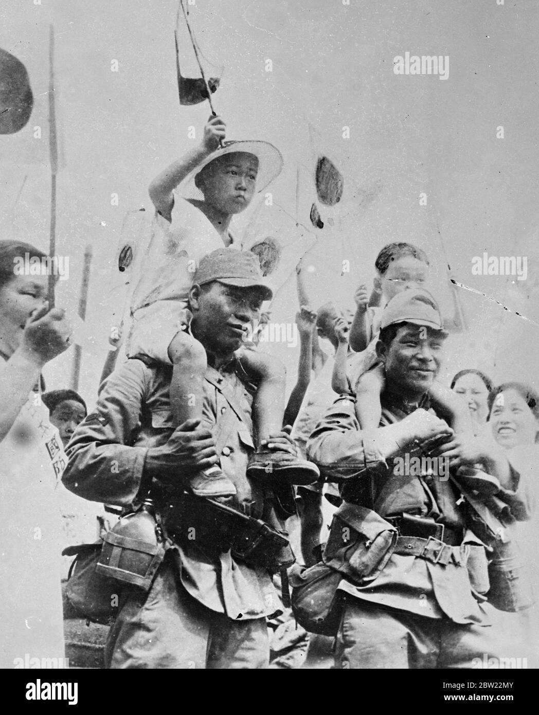 Japanese children perched on the shoulders of a smiling pair of soldiers, greet their troops as they halt at a Japanese settlements during the advance in North China. Chinese residents in America are gathering supplies for their stricken compatriots in the war areas. 16 September 1937. Stock Photo