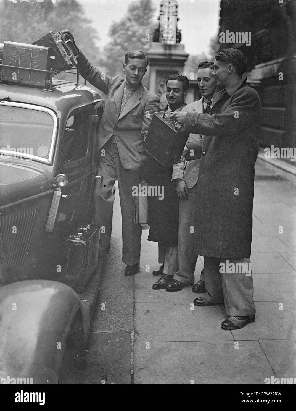Four English boys began their new career in adventurous style when they left the India Office in London to travel by car all the way to Calcutta take up positions in the Indian Civil Service. The four boys: A W Flack, T. N. Kaul, F. A. Sharpe and P. F. Adams loading their car with petrol before leaving London. 21 September 1937. Stock Photo