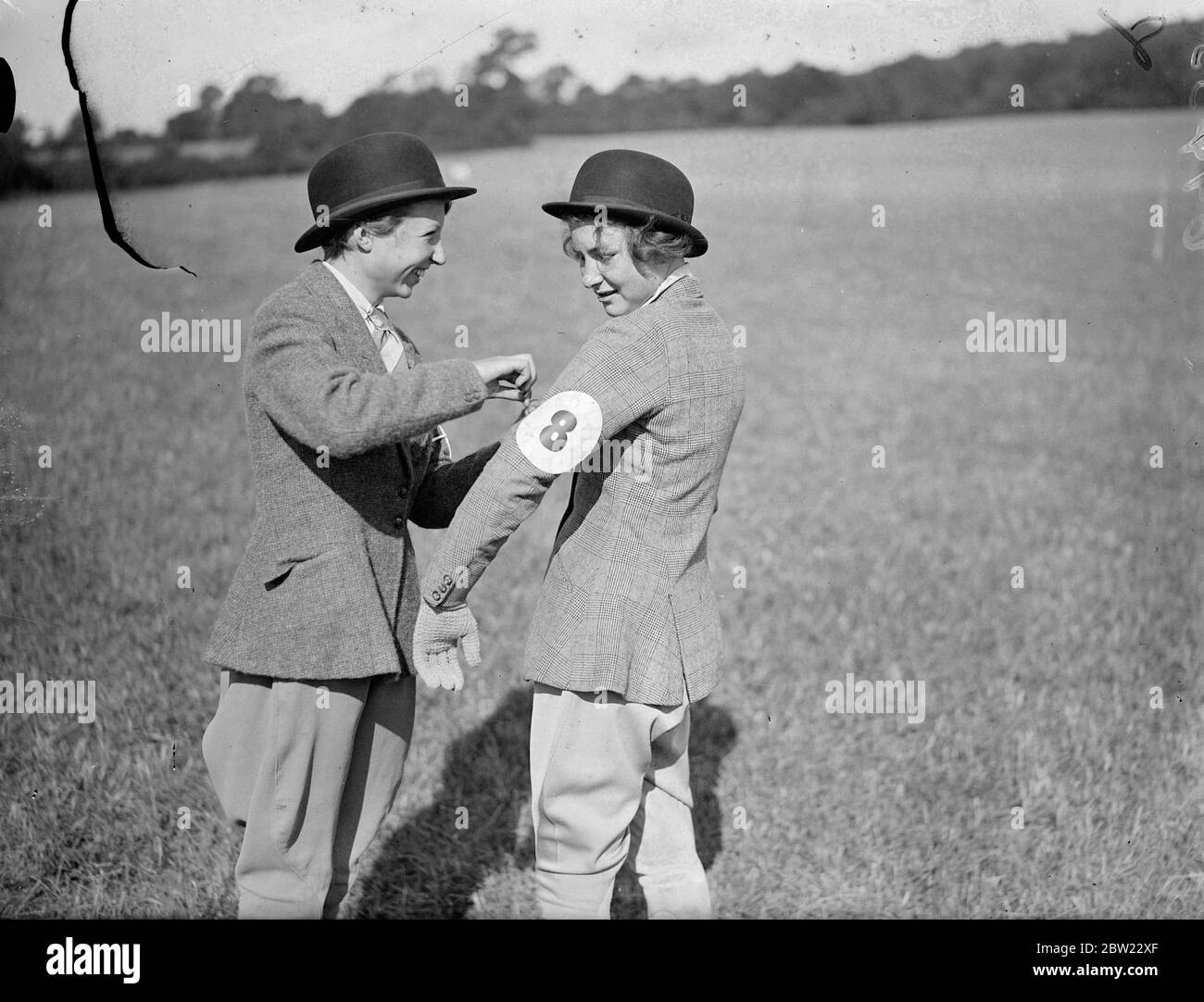 14 year old Miss Jones Williams (left) adjusting the number of Miss C Barton. aged 17. The Lockner riding school's horse show and Gymkhana was held at Sherborne Farm, Shere, Surrey. 18 September 1937. Stock Photo