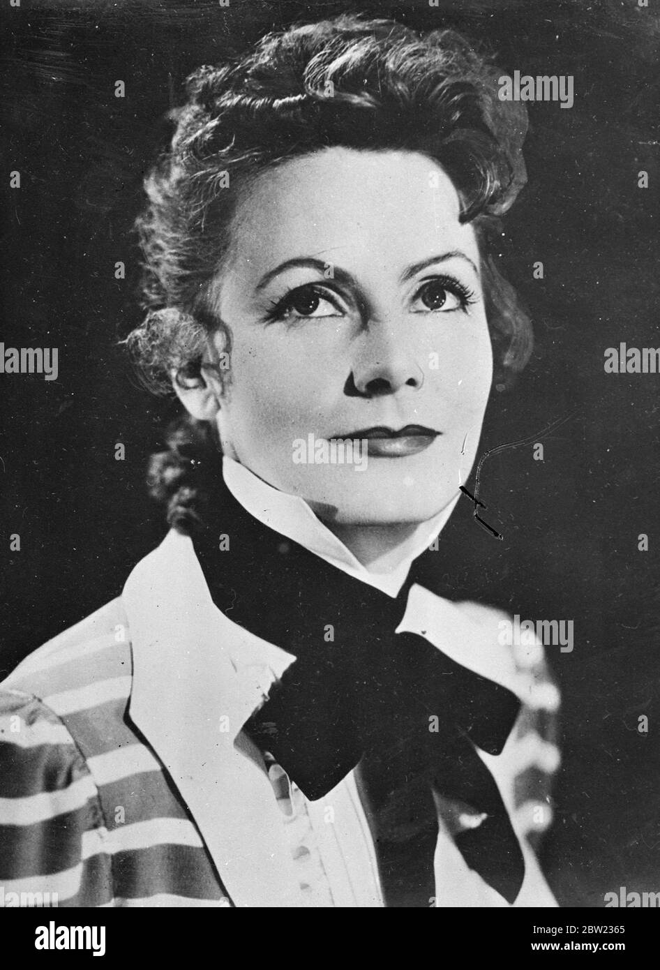 Greta Garbo's new hairstyle, in which curls have taken the place of the almost severe style of former days, is seen in this picture for which she posed in costume between shots of her new film Conquest at the Metro-Goldwyn-Mayer studios in Hollywood, California. She plays opposite Charles Boyer. 22 September 1937 Stock Photo