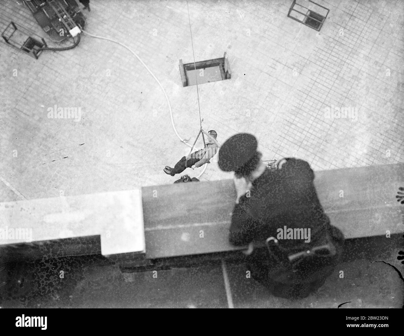 Fireman at the new headquarters are practising the display they would give when the King and Queen open the new Fire Brigade Headquarters on the Albert Embankment, London today (Wednesday). The new building is of steel construction and is nine storeys high. Photo shows ; A man being rescued in a sling from a  burning  building during the display practise. 21 July 1937 Stock Photo