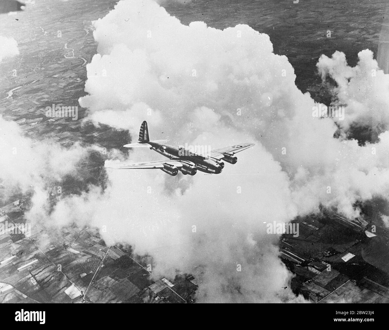 An American Army Air Corps Flying Fortress winging its way through the banks of clouds , 13,000 feet over Dayton , Ohio. This type of army plane is powered by four engines and is covered at every vulnerable point by gun turrets. 22 July 1937. Stock Photo