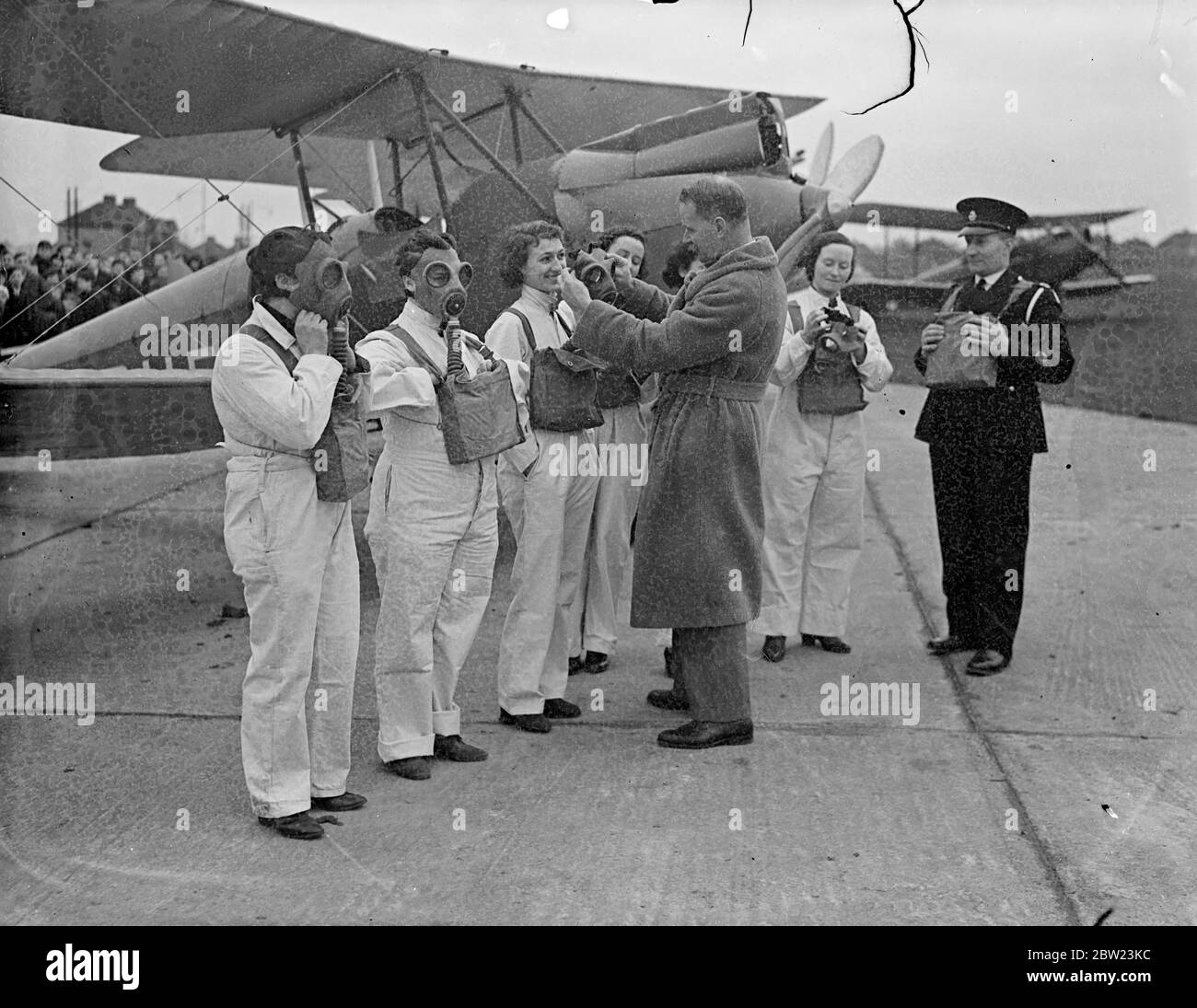 Mayor of Romford sees air girls, anti air raid training. The Mayor of Romford, councillor C H Allen, J P, visited Marylands Aerodrome, near Romford, Essex, today (Sunday) to see the training of members of the women's Aero club, who are receiving instruction in air raid precautions. Photo shows, the Mayor of Romford, councillor CH Allen, JP, adjusting gas masks for women members of the groundstaff at marylands Aerodrome, Romford, Essex. 20 February 1938 Stock Photo