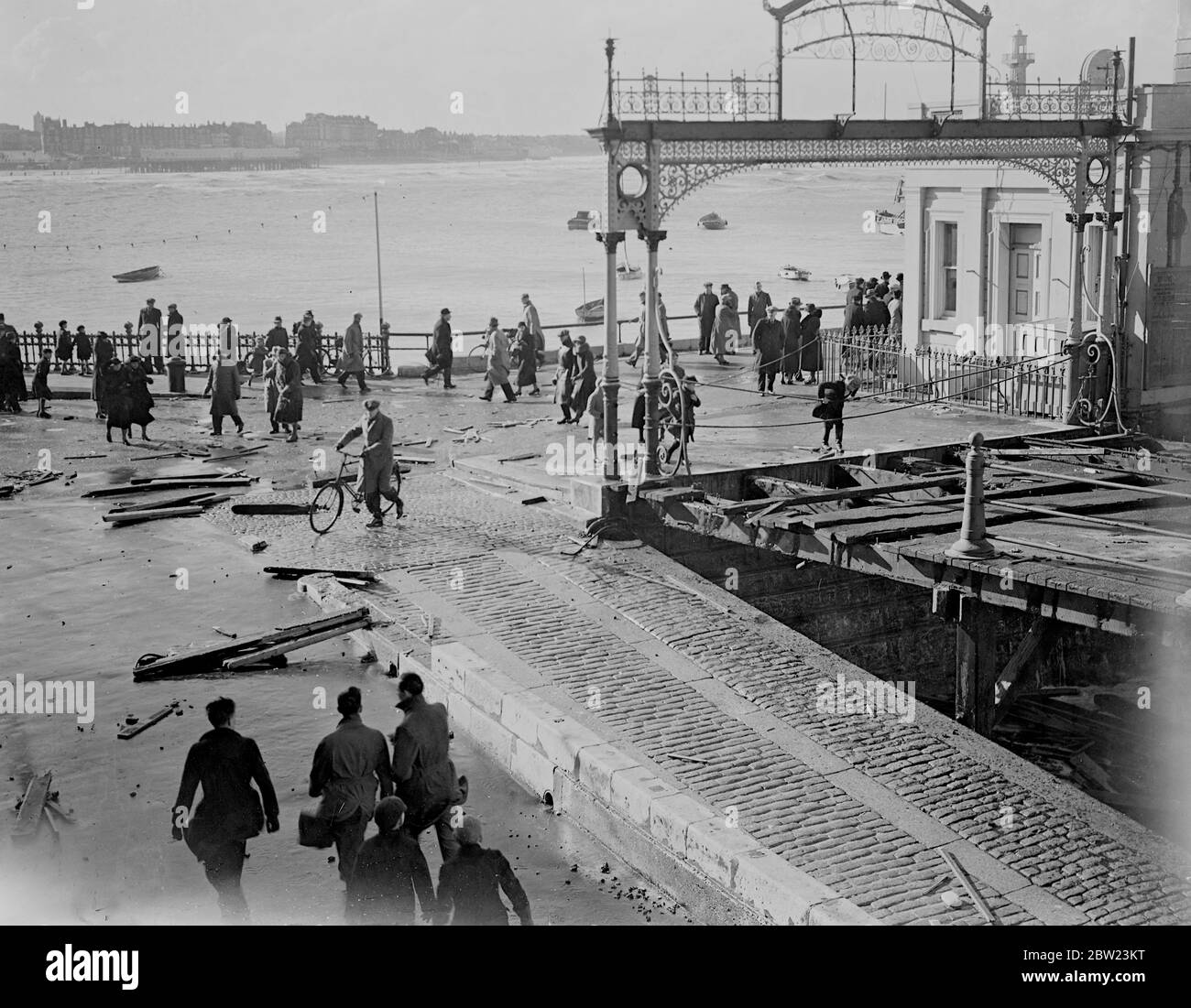Jetty damaged at Margate by worst Gale and 50 years. Sweeping across the South and East coasts, the worst Gale, the England has known for 50 years, left an immense trial of damage behind. Part of the promenade at Margate was torn up, the jetty smashed, kiosks and bathing huts on the beach were overturned by the winds by the wind and battered by the huge seas that smashed over the front. Photo shows, the damaged jetty at Margate, showing the broken woodwork scattered over the front today (Sunday). 13 February 1938 Stock Photo