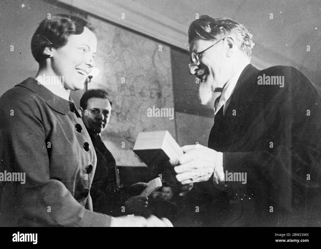 Woman worker receives high Soviet labour order from Kalinin. Bearded M I Kalinin, Chairman of the Presidium of the Supreme Soviet, presenting to smiling Mlle Matveeva the Order of the Red Banner of Labour for her outstanding services to the country, the presentation was made in the presence of members of the Presidium at a meeting in Moscow. 15 February 1938 Stock Photo