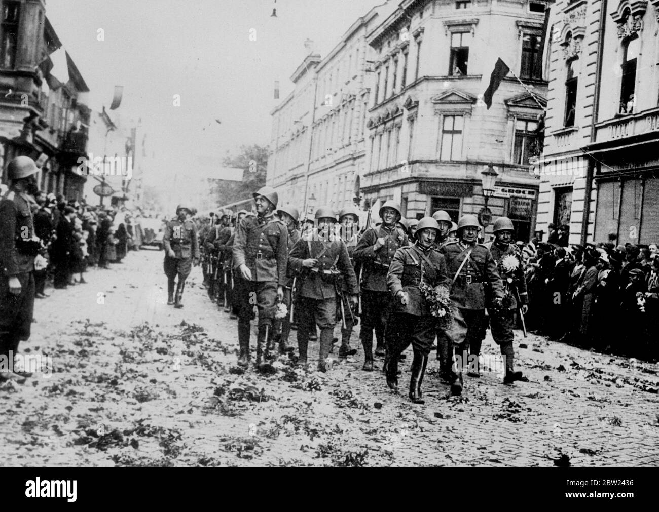 Polish forces are now in occupation of Teschen, the Polish minority district, which was ceded to Poland by Czechoslovakia in compliance with the ultimatum from Poland. The Polish demand came simultaneously with a German diplomat victory in the Sudetenland disputes. Photo shows: Polish soldiers marching through a flower strewn street as they enter the town. October 1938 Stock Photo