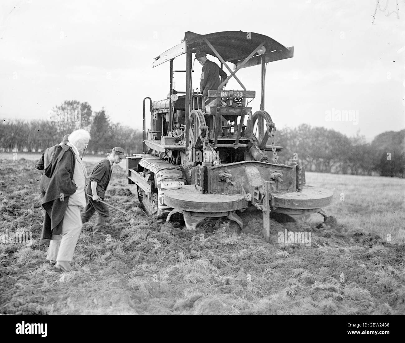 Employing a new gyro-tiller, a plough for digging, and men working day and night shifts. Mr Lloyd George, veteran politician who is now 75, is turning 160 acres of idle land into a market garden in record time. The land, which adjoins his farm at Churt, Surrey, has not been intensely cultivated for many years but already half acreages is ready for planting. The men work at night by searchlight. Photo shows: Mister Lloyd George watching the rotating gyro tiller at work on his new farm. 17 October 1938 Stock Photo