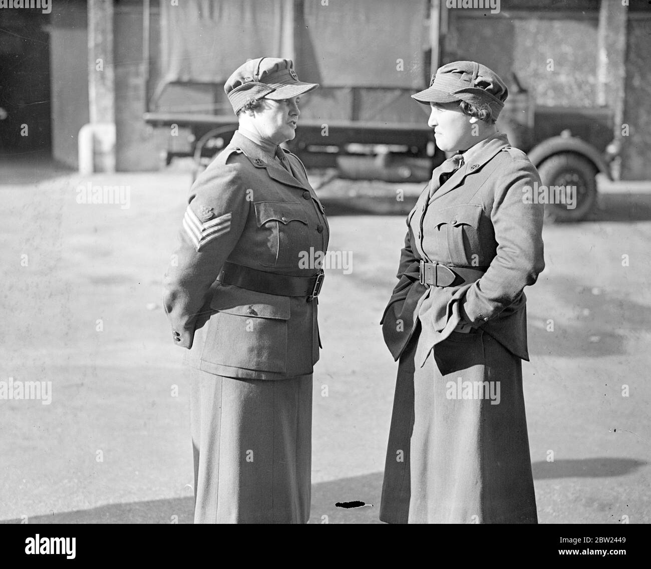 Members of the newly formed Women's Auxiliary Territorial Service, already familiarly known as WATS paraded at the Duke of York's headquarters in Chelsea, London, where they are trained. The members of the service will be used in the event of war for transport, cook houses and canteen duties. Photo shows: A woman member of the service talking to the Sergeant, hands in pockets. 17 October 1938 Stock Photo