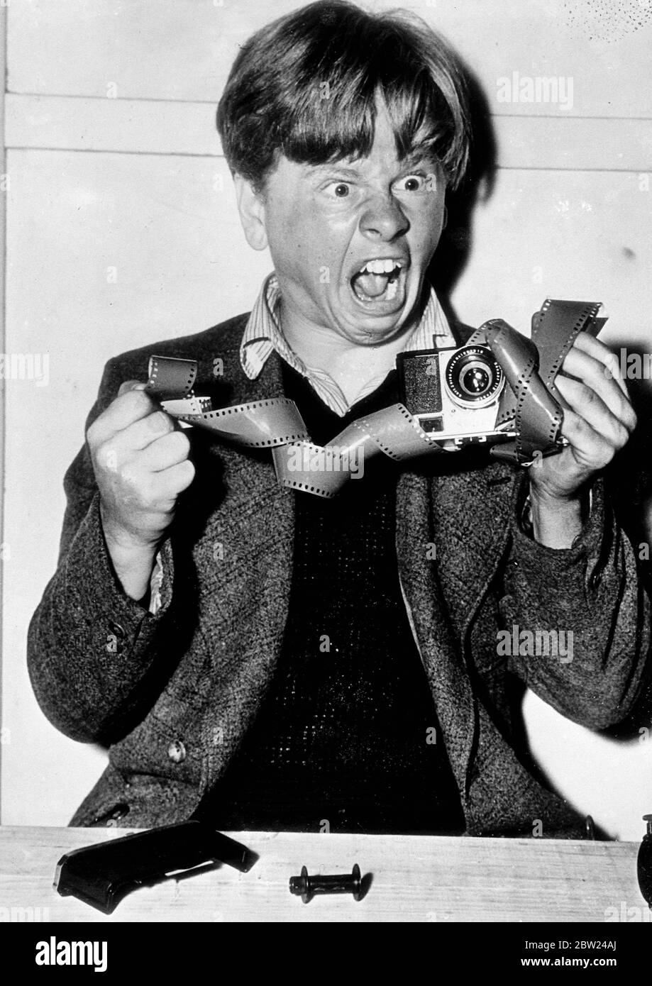 Mickey Rooney, the young film actor, who appears in 'Boys Town' is one of Hollywood's 'candid camera' friends, but has himself been caught by candid camera in this series as he gives a lesson on loading. It seems he has a long way to go before becoming an expert. Photo shows,Mickey Rooney's Irish temper flares up as the film refuses to go into the camera magazine. Stock Photo