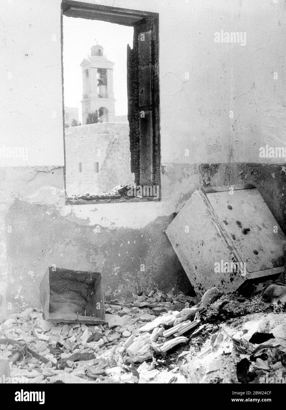 The most daring exploit so far of the Arab rebels in Palestine was the invasion of Bethlehem. The chief object of attack was the post office in police station, both have been gutted during the rebels occupation of the city. The police station was situate where Christ was born. Photo shows: A scorched safe amid the ruins of the first floor of the police station building which was given over to the law court. All official records of civil and criminal cases were destroyed in the fire. Through the window is seen one of the towers of the Church of the Nativity. 19 September 1938 Stock Photo