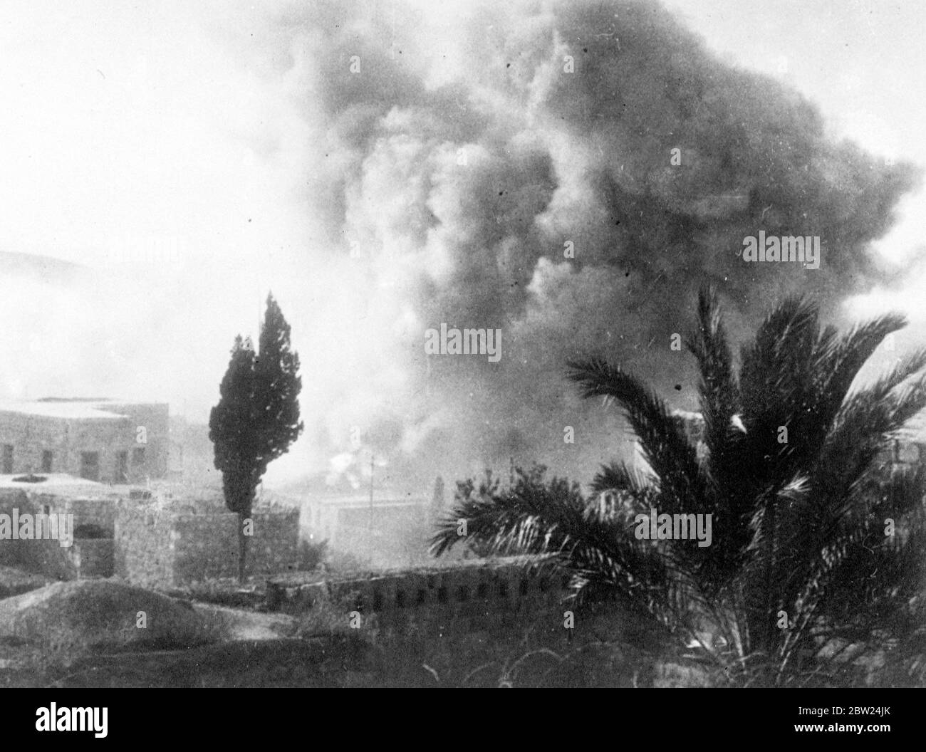 British troops, blow up 100 Arab houses in Palestine town. Royal Engineers dynamited over 100 Arab houses in Jenin, Palestine, following the murder by Arabs and Assistant District Commissioner Moffett of Jenin. The houses were destroyed, partly as a punitive measure against the inhabitants of the town having harboured Arab rebels and partly for reasons of security, houses in Jenin was built so close to one another that police and military patrolling was impossible. Photo shows, the pall of smoke and dust as the houses were blown up. 5 September 1938 Stock Photo