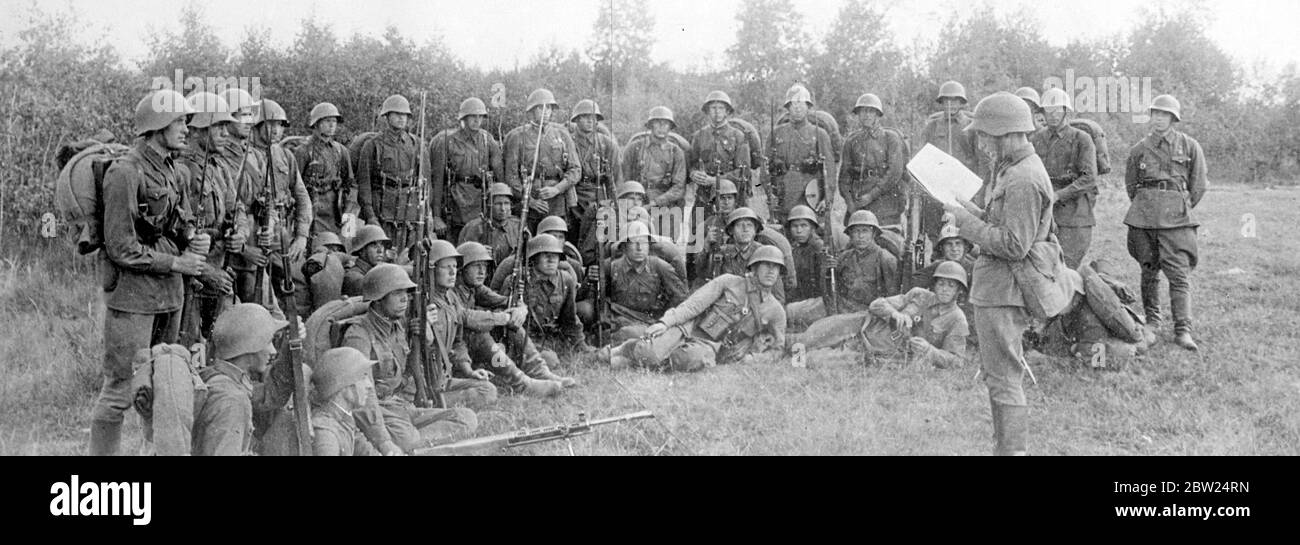 Soviet troops hear news of peace with bayonets at the ready. Soviet troops, would bayonets bristling,, listening attentively as the news of the armistice on the Soviet Manchukuo border was read to them in a field in the Moscow military district. The determined expressions of the soldiers seem to support the declaration of the unit that they would 'crush', at any moment, the enemy attempting to infringe the sacred soil of the socialist fatherland. 21 August 1938 Stock Photo