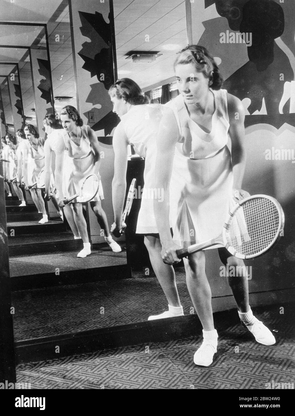 Kay Stammers designs own tennis dress. Kay Stammers, the attractive British tennis player, uses a series of mirrors to display a new tennis dress she designed herself in New York. The dress of white linen edged with pink. 5 September 1938 Stock Photo