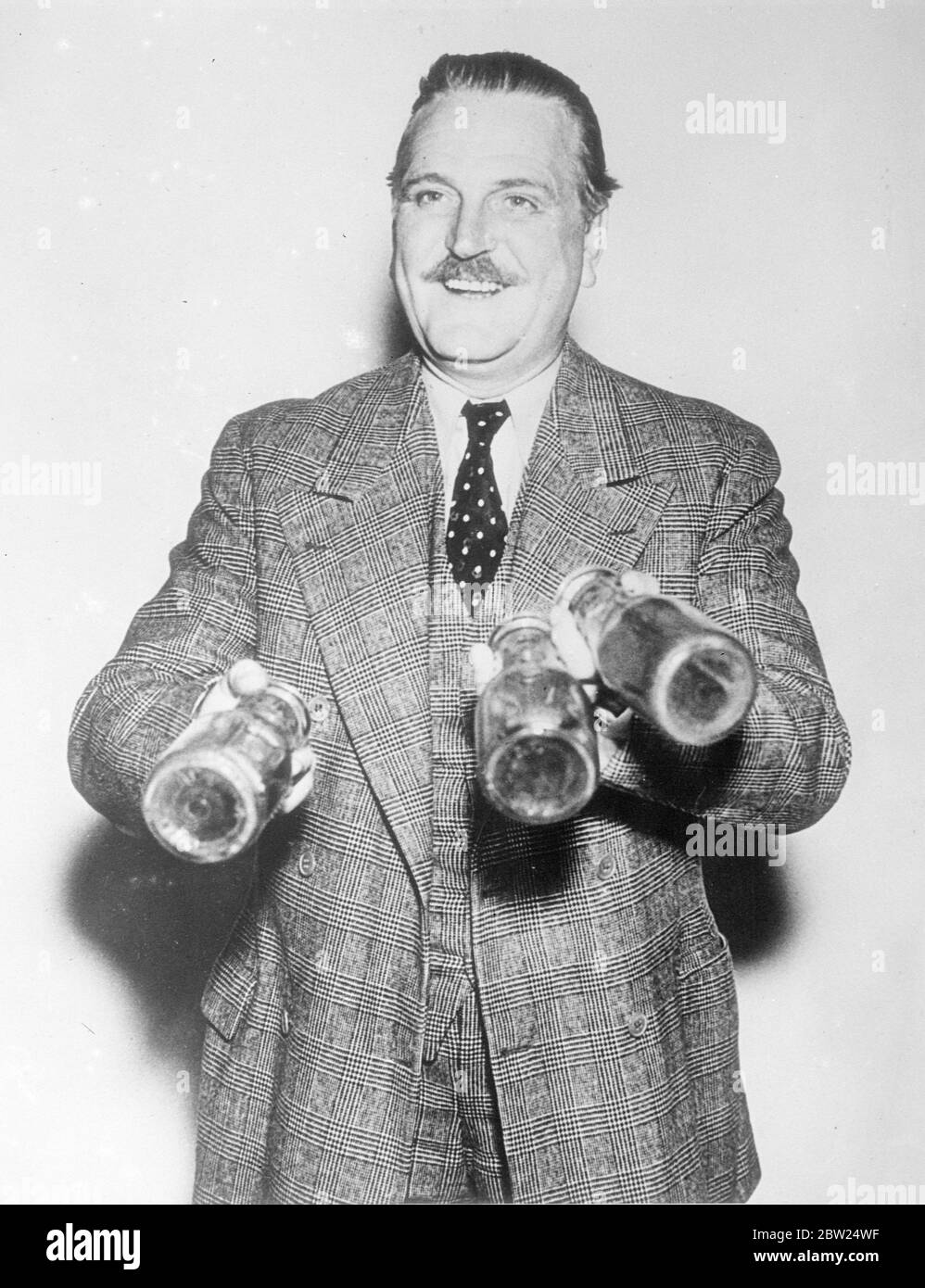 Film actor turns conjuror and gets a surprise. Using three empty milk bottles, and a lot of hope, Frank Morgan, one of Hollywood's best feature players who is famous for the jovial types, he portrays on the screen, set out to entertain his friends with a juggling act. His confidence was misplaced, however, for he lost control of a bottle and only found it when it hits him on the head. Photo shows, Frank Morgan with a smile of extreme confidence, gaily steps up with his three milk bottles to amuse his friends. Stock Photo