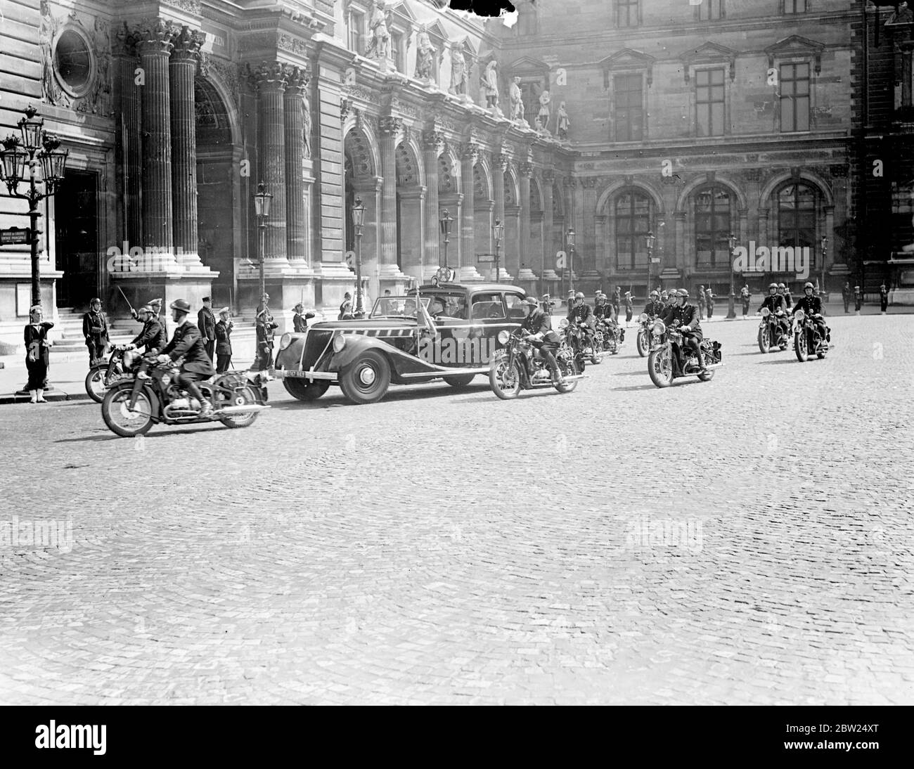 King and Queen visit British art exhibition at the Louvre. Driving in a close car with an escort of motorcycle police, the King and Queen visited the Exhibition of British Art at the Louvre in Paris. They were accompanied by Pres and Mme Lebrun. Photo shows, the King and Queen arriving at the louvre with their escort. 20 July 1938 Stock Photo