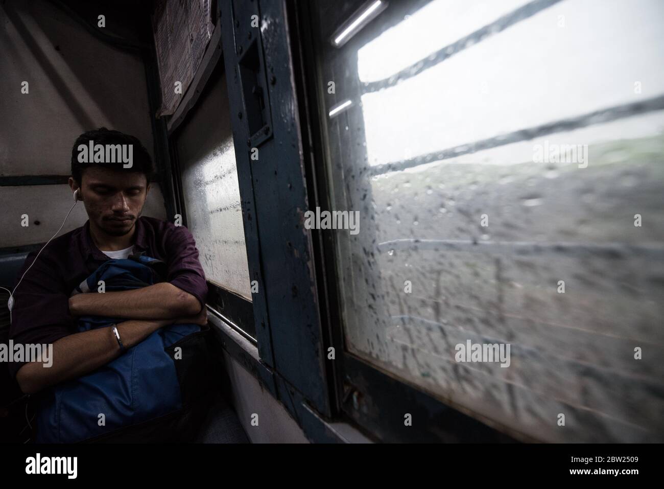 Man looking out window of moving second class train. Indian Railways. India. Stock Photo