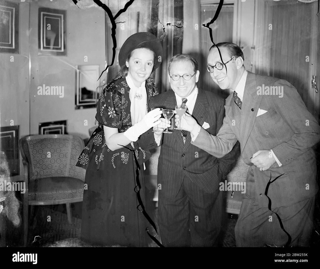 Jessie Matthews toasts Louis Levy's new BBC venture. To celebrate the commencement of Louis Levy's contract with the BBC for his Augmented Variety Orchestra of 30 musicians, a cocktail party was given at the Savoy Hotel, Strand. Leading figures in the entertainment world were present. The Orchestra will appear in 'You Shall have Music', which has been booked for twelve weekly broadcasts. Photo shows, Jessie Matthews and her husband, Sonnie Hale, toasting Louis Levy at the cocktail party. Miss Matthews is singing in the first programme. 5 July 1938 Stock Photo