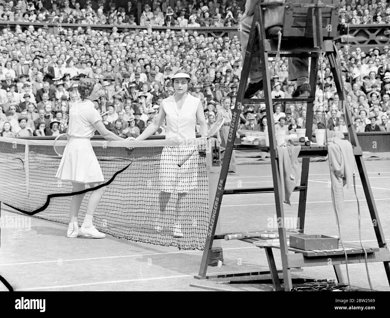 Helen Jacobs rests after leg gives way in Wimbledon Final. Miss Helen Jacobs had to rest after her leg gave way in the second set of her match agaist Mrs Helen W ills Moody in the final of the women's singles at Wimbledon. Mrs Moody won her eigth final 6-4, 6-0. This was the fourth time they had met in the finsl. Photo shows, Mrs Helen Wills Moody and Mrs Helen Jacobs shaking hands after their match. 2 July 1938 Stock Photo