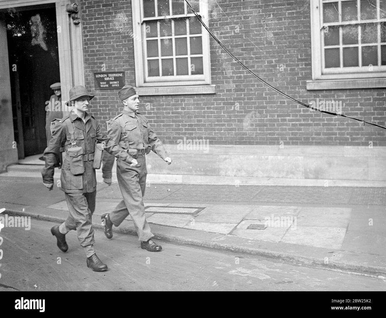 Army's experimental clothing on view in London. The experimental design of clothing for active service and training, which is to form the subject of trials by the army this year, was on view at the Central London Recruiting Depot, Great Scotland Yard, Whitehall. The equipment has been designed with a view to lightening as far as possible the weight carried by the soldier and taking into consideration mechanisation and the new weapons which have been adopted. Photo shows, soldiers walking in the two experimental uniforms, basic equipment with web pouches for Bren gun magazines, etc. (left) and Stock Photo