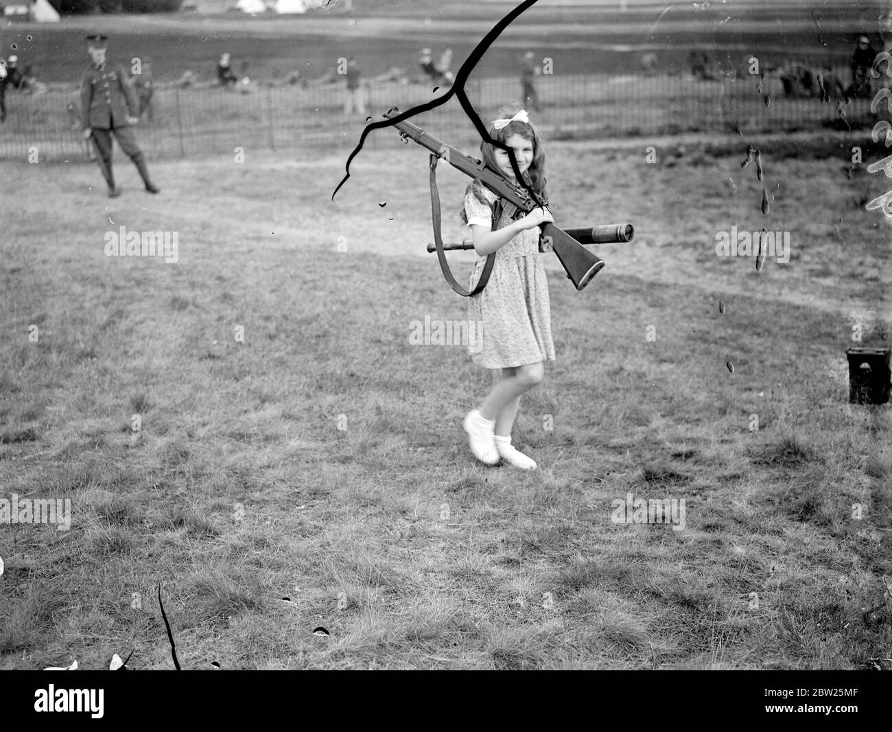 Shouldering arms for father at Bisley.. The Imperial meeting of the National Rifle Association, lasting a fortnight, has opened at Bisley Camp. Chief competitors of the first day were the 'Queen Mary', the 'Whitehead' and the 'Eandco'. Photo shows, little Miss Denise Philpott, carries the rifle and telescope for her father, Mr C H Philpott, at Bisley. 4 July 1938 Stock Photo