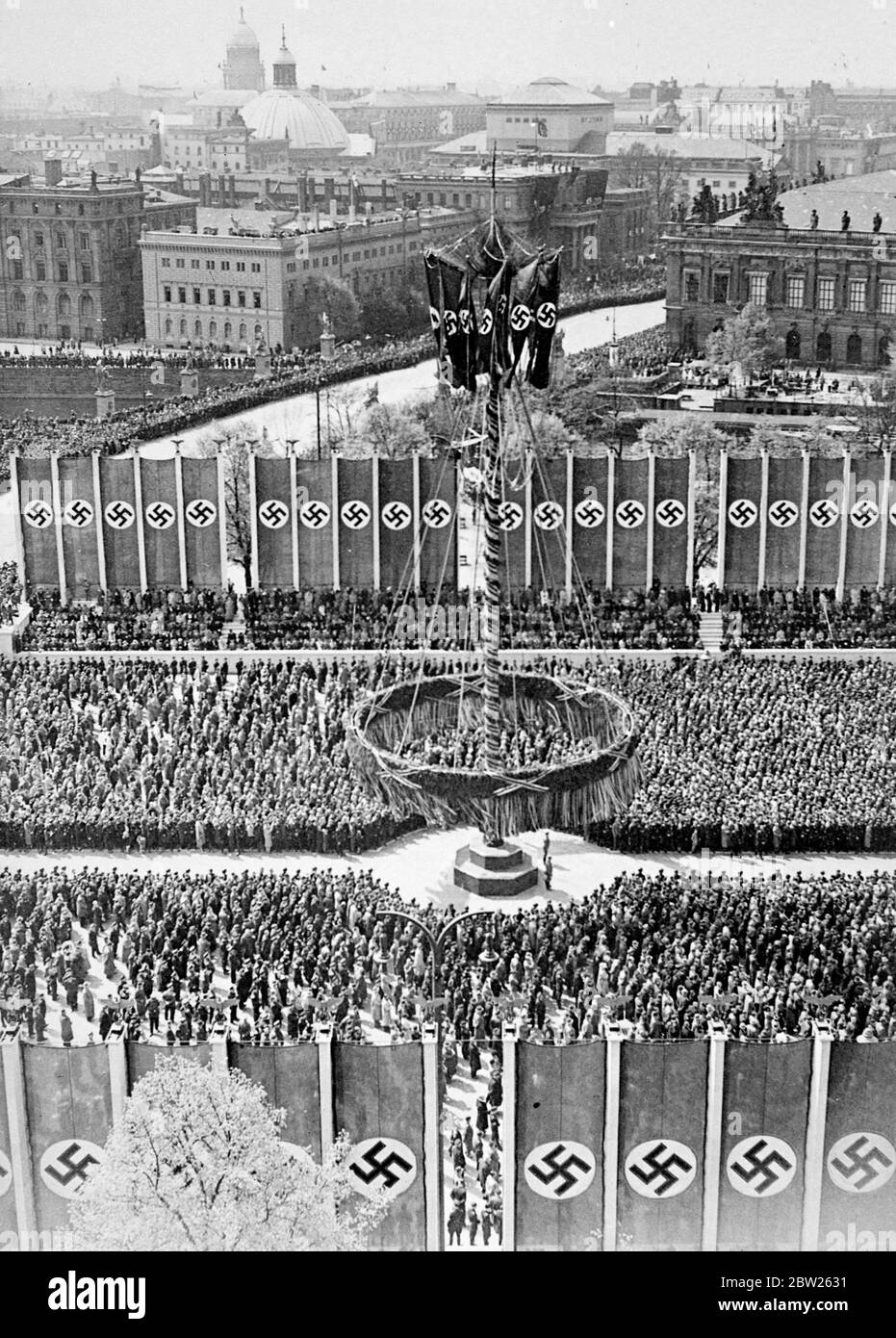 Thousands of workers gather around Maypole to hear Hitler's speech. The great crowd of workers gathered around a Maypole nearly 100 foot high, on the Berlin Lustgarten to hear the May Day speech by Herr Hitler. The Maypole have been specially sent from Austria. In his speech Hitler complained about Germany's 'lack of space' and claimed that Germany was far ahead of democracies in achievement. 2 May 1938 Stock Photo