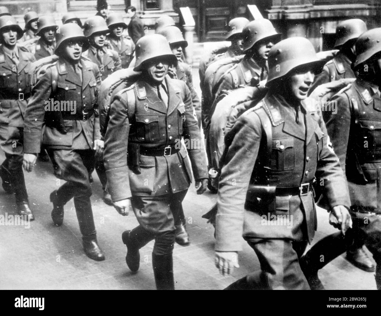 Austrian Legion features in triumph to Vienna. Returning in triumph to their homeland after years of exile, the first detachments of the Austrian Legion marched through Vienna in steel helmets and Nazi uniforms. The Legion consist of Austrian Nazis who had sought refuge in Germany before the annexation of Austria by Germany. Photo shows, the Austrian legionnaires singing as they marched through Vienna on their return. 28 March 1938 Stock Photo