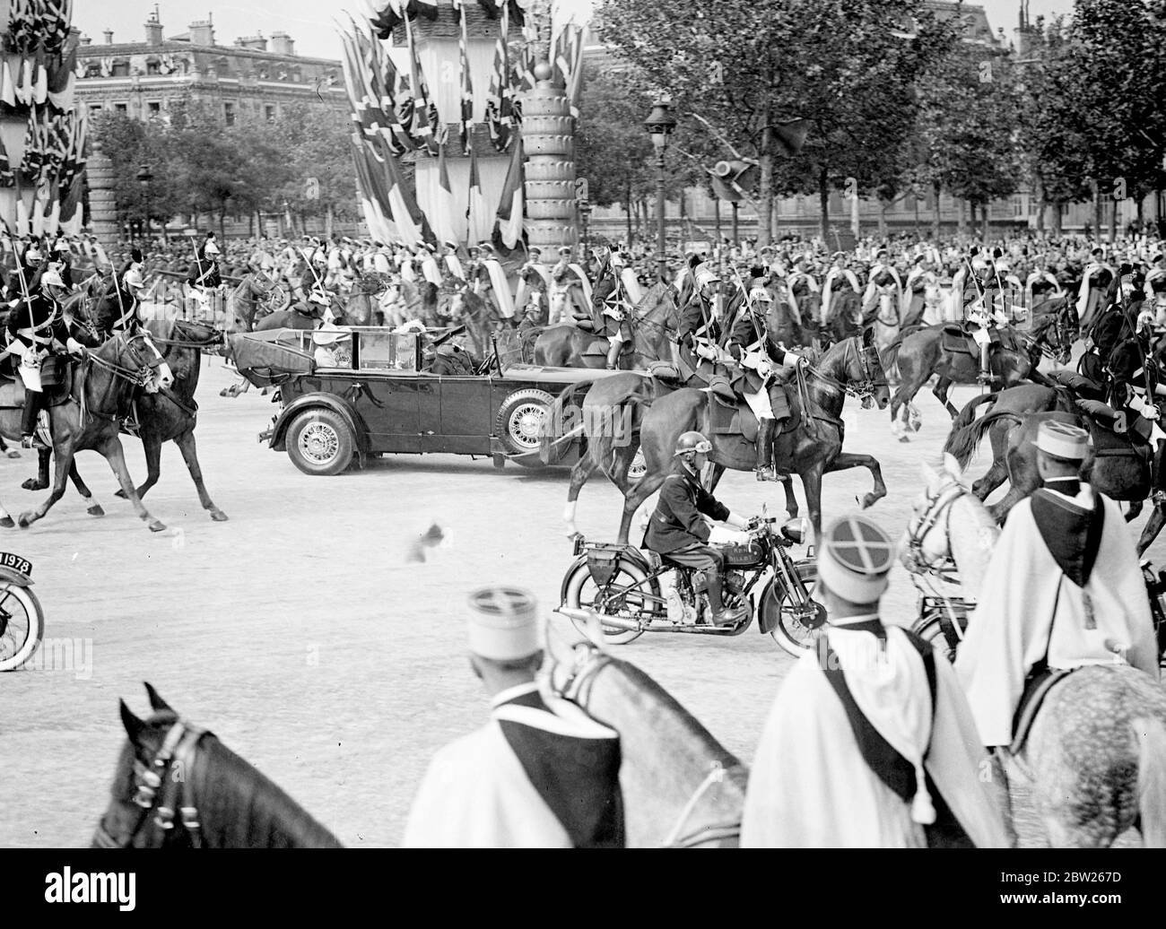 King and Queen receive tumultuous welcome in Paris. Welcomed by 1 million cheering people and the thunder of 101 gun salute, the King and Queen arrived at the Gare Bois de Boulogne on their State visit to Paris. Accompanied by President Lebrun of France and Mme Lebrun , they made the 4 mile drive through decorated streets lined with troops and crowds to the Qui d' Orsay Palace , where they are staying. Photo shows, the Queen driving through Paris with Mme Lebrun , escorted by cavalry and motorcyclists. 19 July 1938 Stock Photo