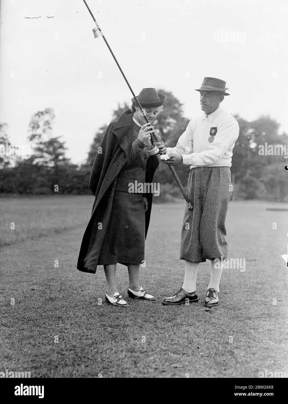Wife helps husband in fly casting competition. Champion fly and bait casters from Britain, the Continent and America competed in the annual international tournament of the British Casting Association at the Ranelagh Club, barnes, London. Photo shows, Madame Gedart, wife of the Belgian Champion, gives a helping hand to her husband, Mons a Godart. Stock Photo