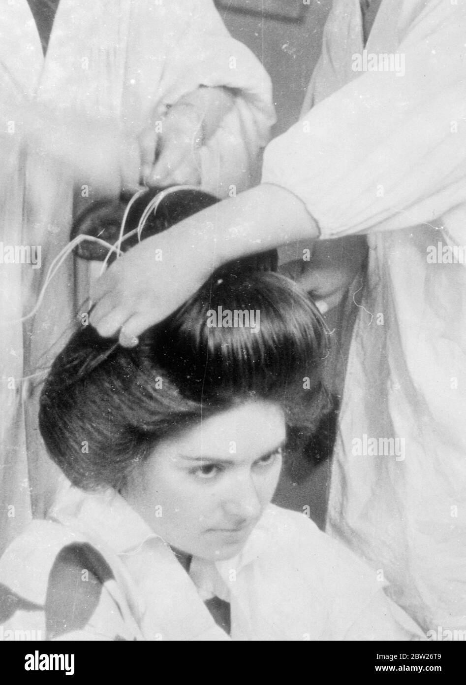 Japanese girls submit to 2 hours agony for alluring coiffure. Few people who admire the beautiful hairdresses of Japanese girls realise the excruciating physical punishment they go through to obtain them. These pictures show the intricate processes which go to make the final effect, after two hours work on the part of the Kamiyuisan (hairdresser). The subject for the pictures, Adrienne Moore, and when the coiffure was finished she said that when reclining in a chair she felt as if Haskell was being told out and found that lying down was almost impossible. Another fact she discovered was that J Stock Photo