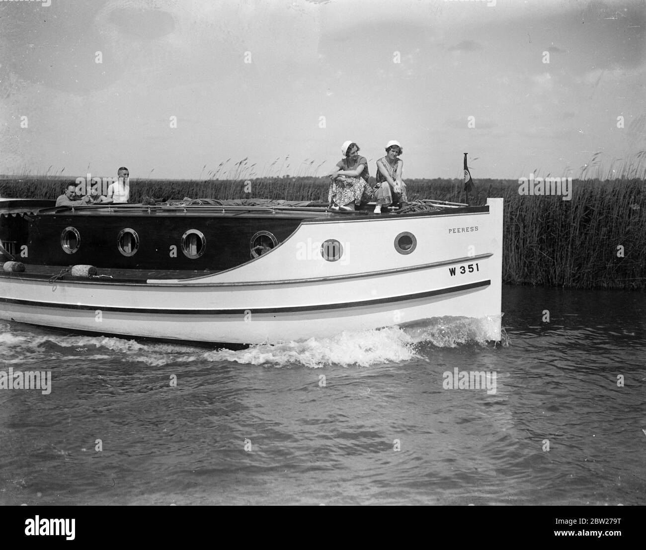 Young men and women sailing through The Broads. 1933 Stock Photo