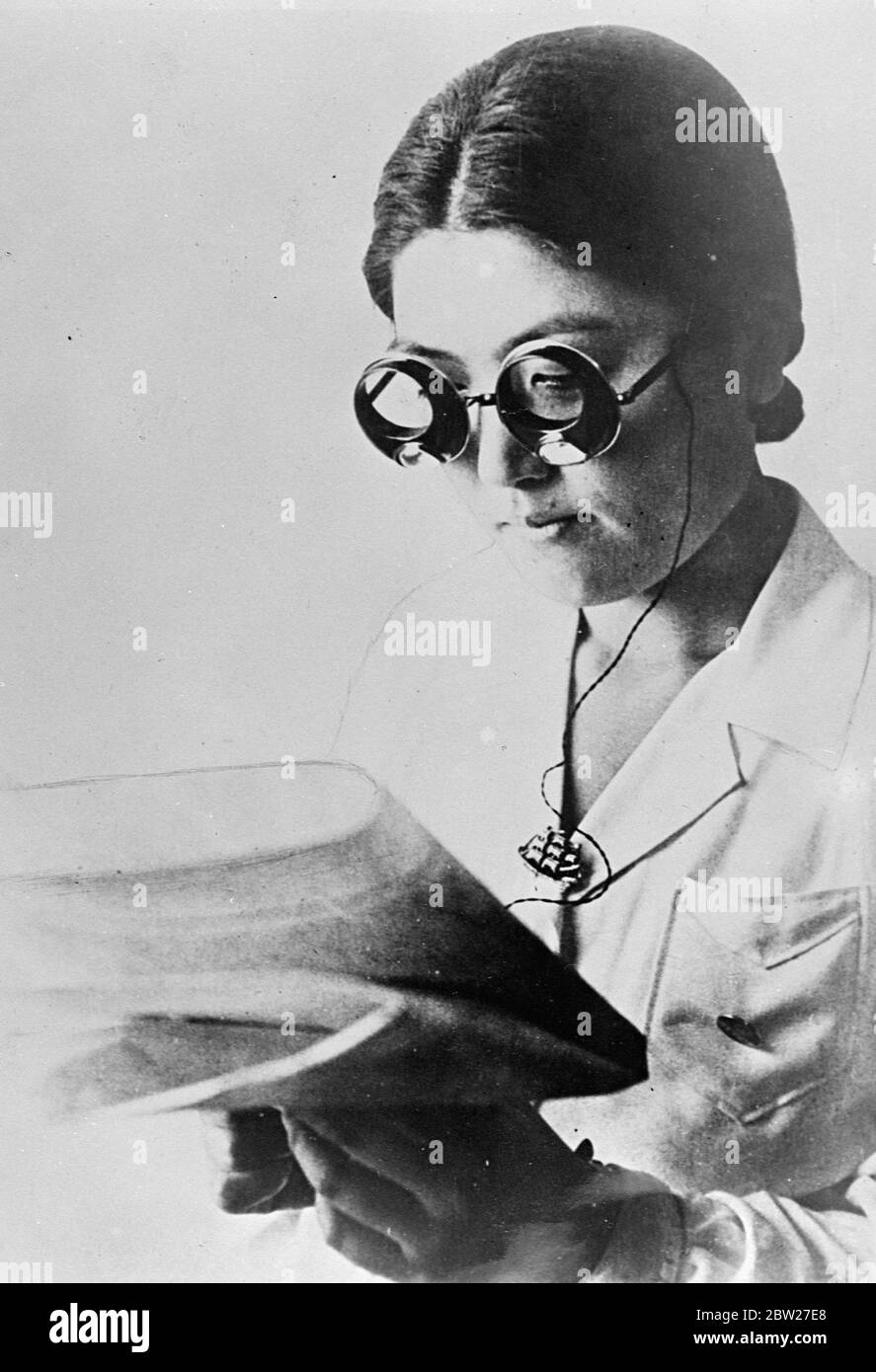 New glasses that cast their own light and enable the wearer to read in an otherwise completely darkened room, have been devised by Japanese. Drawing their current from a small pocket battery, the glasses have twin lights. 14 July 1937 [?] Stock Photo