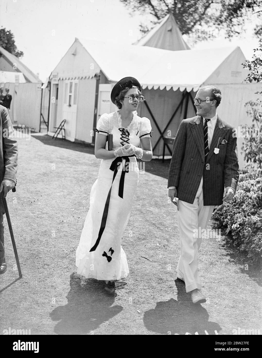 With the heatwave as encouragement, Henley's Royal Regatta vied with Ascot in variety of its fashions. A white fashion relieved by black trimming at Henley. 3 July 1937 Stock Photo