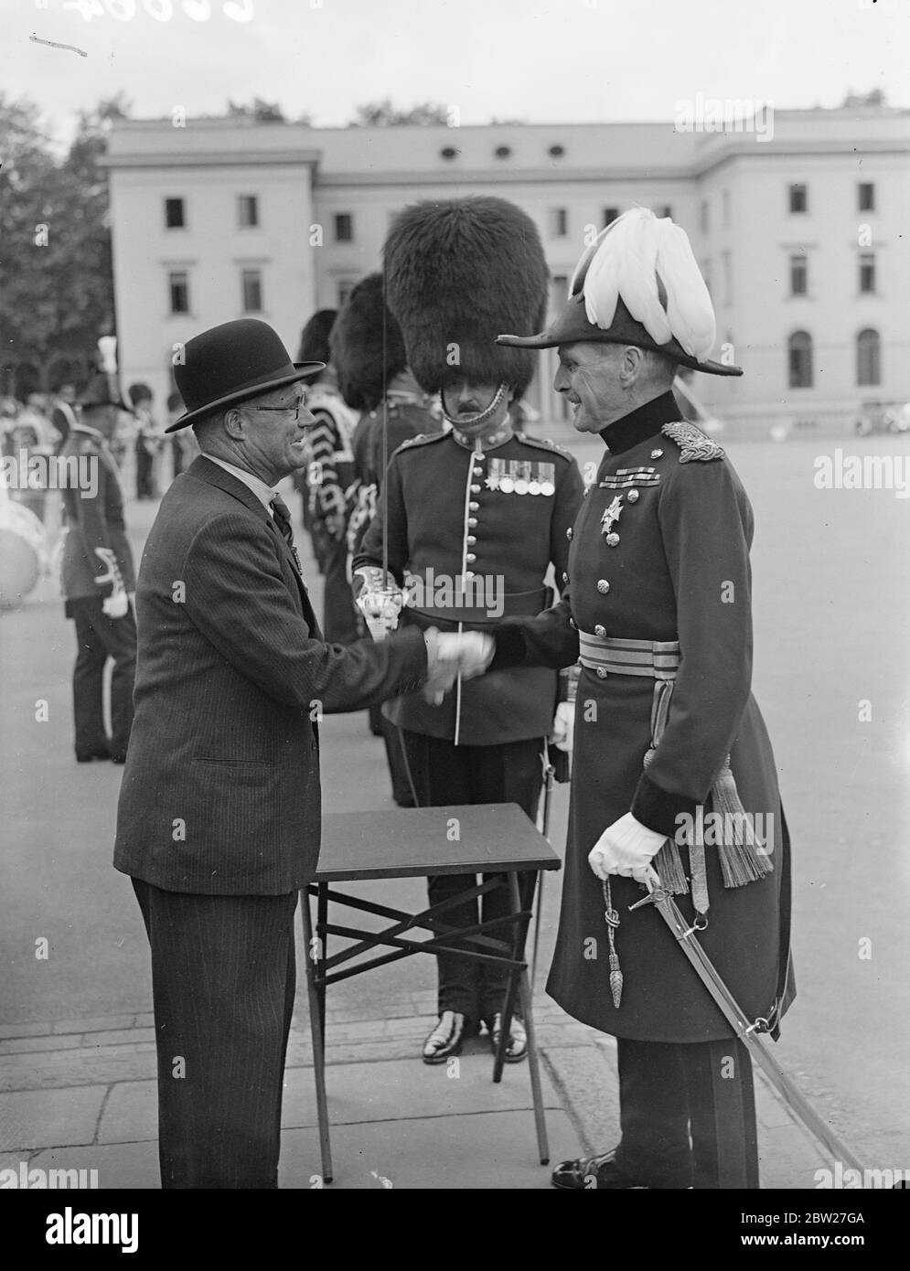 26 years after being recommended for the Meritorious Service Medal, Mr J. Brady received the decoration from Major General B. N. Sergison-Brooke, General Officer Commanding, London District, at Wellington Barracks. When recommended for the medal, Mr Bradey was Acting-Sergeant Major of the Eastern Bengal State Railway Volunteer Rifles, and the Prince of Wales Volunteers (South Lancashire Regiment). Mr Bradley forgot all about the award until he received a letter from the War Office recently. Major General B. N. Sergison-Brooke shaking hands with J Brady at Wellington Barracks. 29 June 1937 Stock Photo
