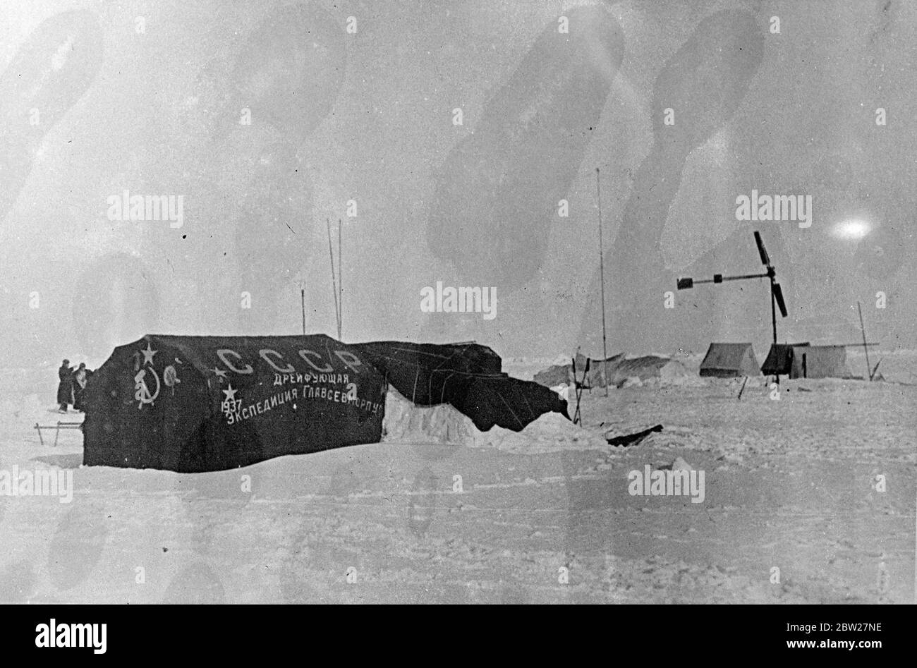 These pictures, the first ever made at the North Pole, were flown to Moscow and from there to London. The Soviet scientific expedition led by Professor Otto Schmidt has succeeded in establishing on an ice floe in the frozen wilderness from which valuable scientific information and regular weather reports are now being sent by radio for the first time in history. The main tent of the expedition bearing the inscription that reads: USSR, the Drifting Expedition of the Chief Administration of the North Sea Route -1937 and the hammer and sickle and the red star communist insignia. 28 June 1937 Stock Photo