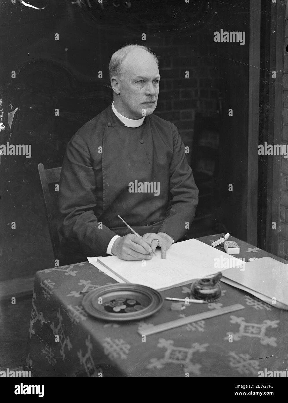 The Vicar of St Thomas Church, North Kensington, the Rev. Pitt-Marson, has started a 13 hours sitting in the porch of his church in Kensal Road to receive gifts for church funds. Before his ordination nine years ago, Mr Pitt-Marson was in the service of the Foreign Office. He is now working in the poorest parish in London. 26 June 1937 Stock Photo