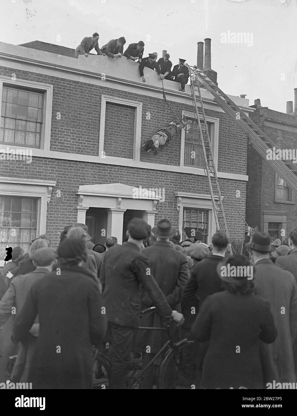 Woman in night clothes threatens to throw herself from roof in Camberwell. Injected by doctors, rescued by firemen. Standing in her night clothes on the edge of the roof of a house in Denmark Road, Camberwell, a woman threatened to throw herself to the ground. Police, firemen and doctors were called by workmen who had been painting the house. Before the woman could be lowered on a stretcher, the doctors had to give her an injection. The woman, taking the workmen by surprise, had run up the ladder they were using and reaching the roof said, 'it won't take me a minute', the men held back while t Stock Photo