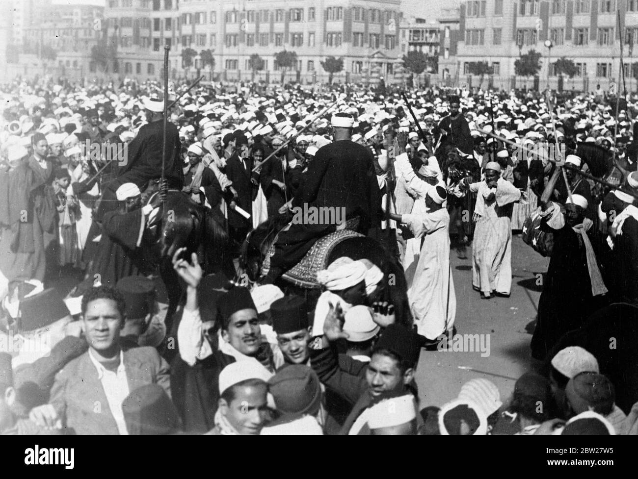 Bedouins dance in Cairo streets as King Farouk is married. With traditional Muslim ceremony, 17-year-old King Farouk of Egypt, was married at the Koubbeh Palace in Cairo, to Miss Farida Zulficar Pasha, the judge of the Egyptian court of appeal. Photo shows, Bedouins, who had come in from the desert to join in celebrations, dancing, near the Abdin Palace in Cairo as the wedding ceremony took place. 23 January 1938. Stock Photo