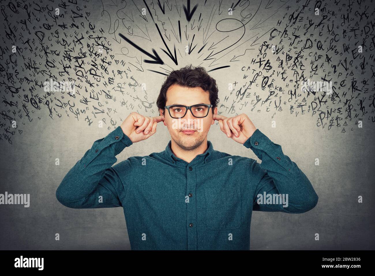 Annoyed businessman covers ears with fingers, looks displeased, refuses