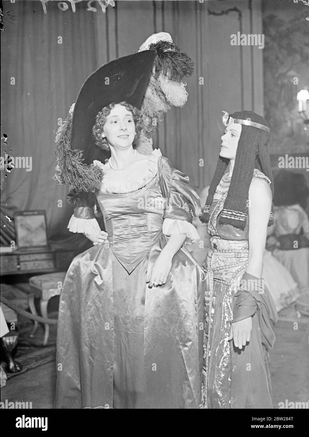 Beauties of the past come to life in London. Well-known women, in costume, are appearing as beauties of bygone days at the Palace of Beauty which has opened at Grosvenor Square, London, in aid of Battersea General Hospital. Photo shows, Nell Gwynn (Miss S Dauncey) left with Cleopatra (Miss Beryl Preston). 12 January 1938 Stock Photo