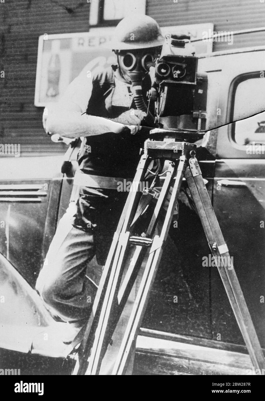 An American news reel cameraman ready for action in a strikers riot ready to go anywhere at any time. Complete with gasmask, steel helmet and a specially reinforced camera. Stock Photo