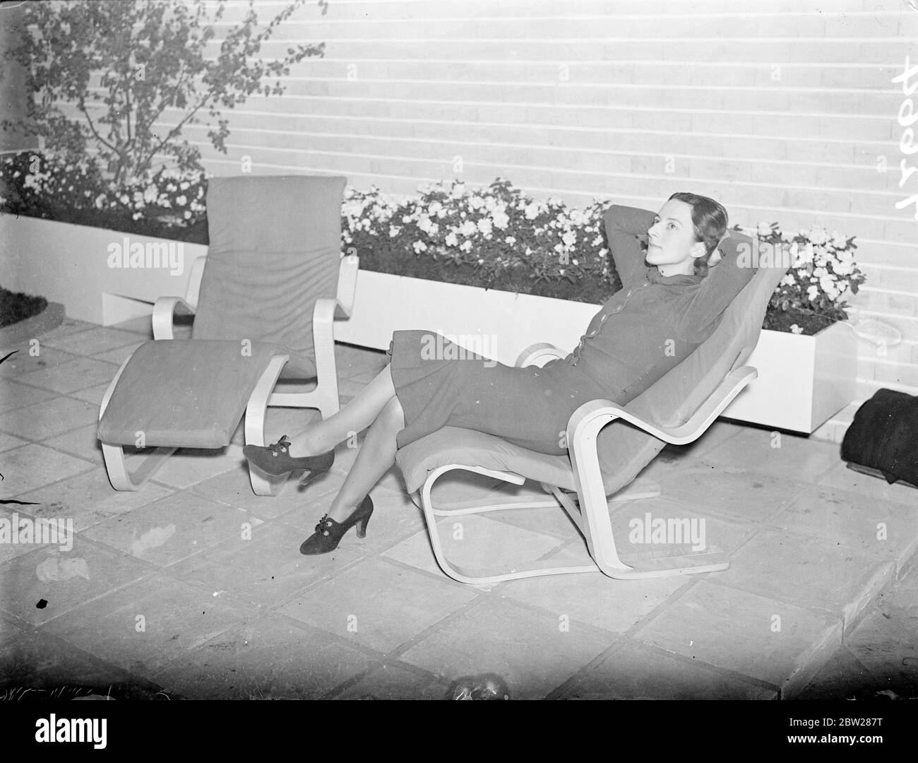 'Easy chair' for the garden at modern architecture exhibition in London. The private view of the Exhibition of the Elements of Modern Architecture, organised by the Marz (Modern Architectural Research) Group took place at the new Burlington Galleries. The exhibition is an exposition of the modern achievements in evolving a new kind of architecture in keeping with modern life, and also shown how new materials and the latest scientific building methods have transformed the appearance of architecture. Photo shows, the latest in a wooden garden chairs on view in a real garden at the Exhibition. 11 Stock Photo