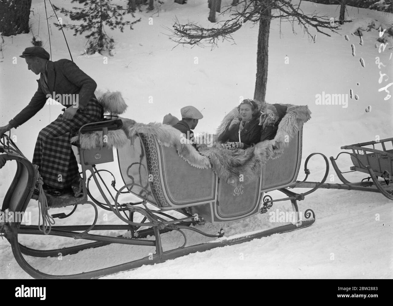 Countess Haugwitz Reventlow goes by sleigh. Countess Barbara Haugwitz Reventlow adjusting her sunglasses as she rode in a sleigh through the snow at St Moritz, Switzerland, where she is holidaying with her husband and baby son. With her in the sleigh is the Hon Mrs Drogo Montagu, daughter of Lord Beaverbrook, the newspaper proprietor. Countess Haugwitz Revetlow, the former Barbara Hutton, Woolworth heiress, recently announced her American nationality. 1 January 1938 Stock Photo