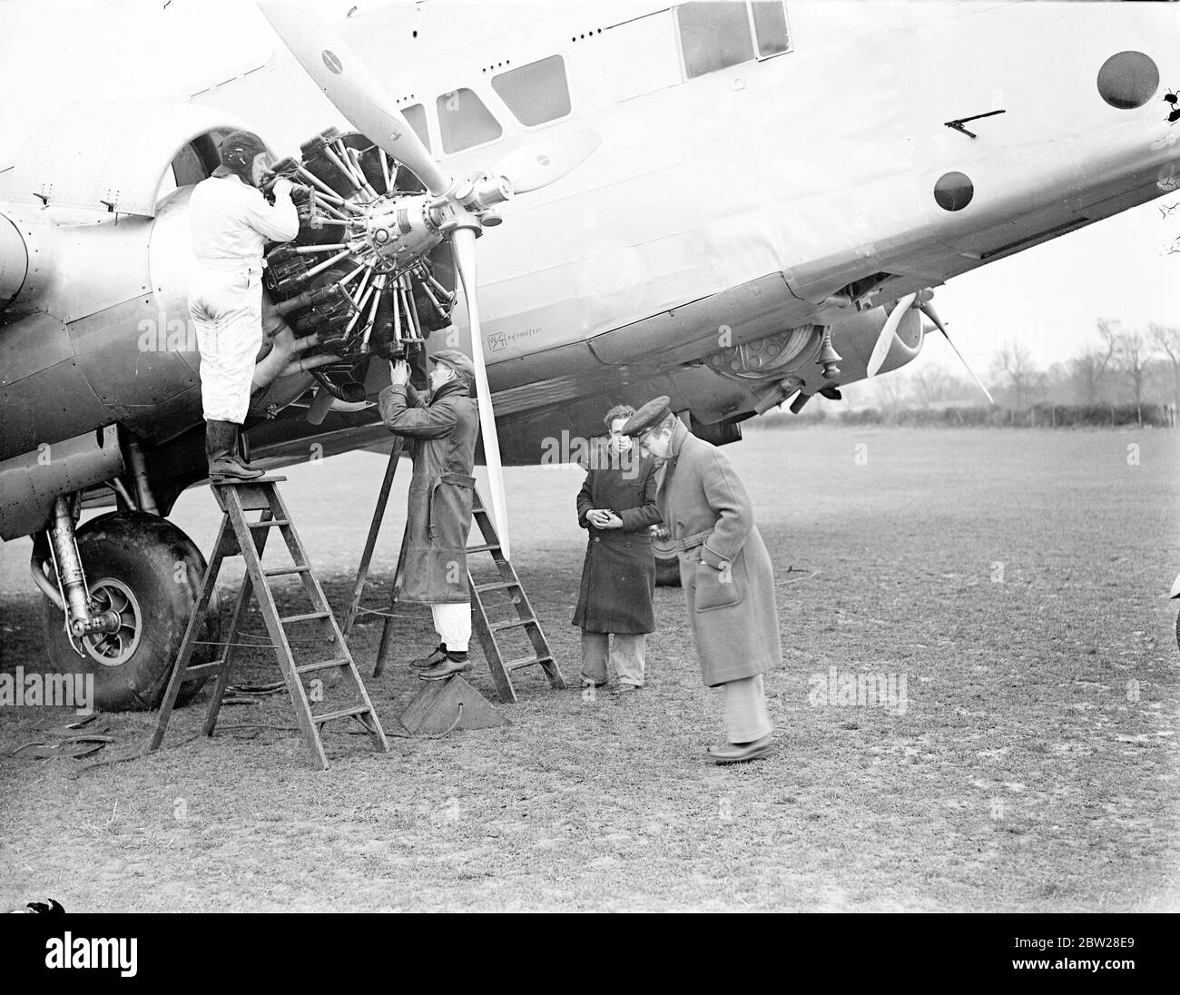 New device for refuelling airliners in the air, invented by Sir Alan Cobham. A new device for refuelling airliners in the air has just been invented by Sir Alan Cobham, the famous airman. The hose which is used to convey the petrol from one machine to the other is rolled on a sport, built into the under part of the fuselage of the refuelling plane. Photo shows, Sir Alan Cobham (right foreground) watching a plane being fitted with his device at an airport near Southampton. The hose sport is seen fitted under the fuselage on right. 13 January 1938 Stock Photo