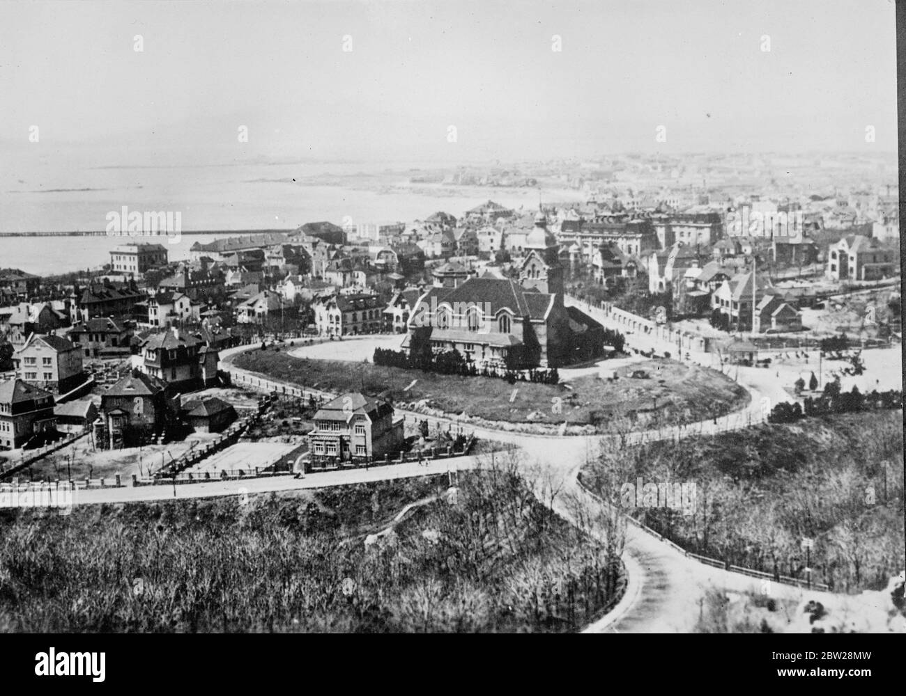 Japan starts big attack on Tsingtao, the northern treaty port in China, while the evacuation of British and American refugees were still being carried out by warships. Japanese warships hurled tons of incendiary explosives into the city is error planes roared overhead. Tsingtao was plunged into confusion, the mob indulging in an order of looting and shooting. The fall of the city is believed to be imminent. 30 December 1937 Stock Photo